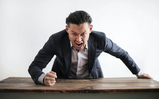 An angry man yelling and banging his fist on a desk