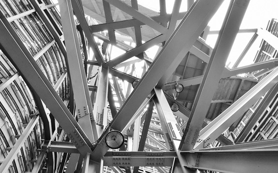 A grayscale photo of metal beams forming a structure for a building