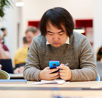 Chinese student on browsing though his mobile phone.