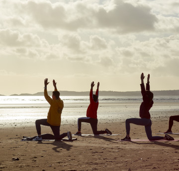 Students doing yoga on the beach