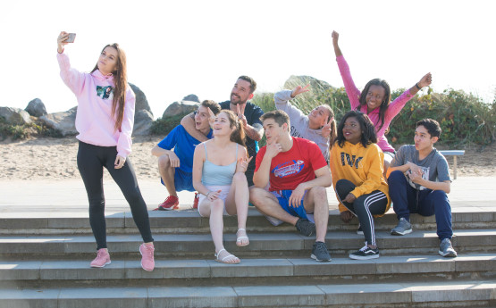Image shows a group of students, posing for a selfie sitting on some concrete steps.